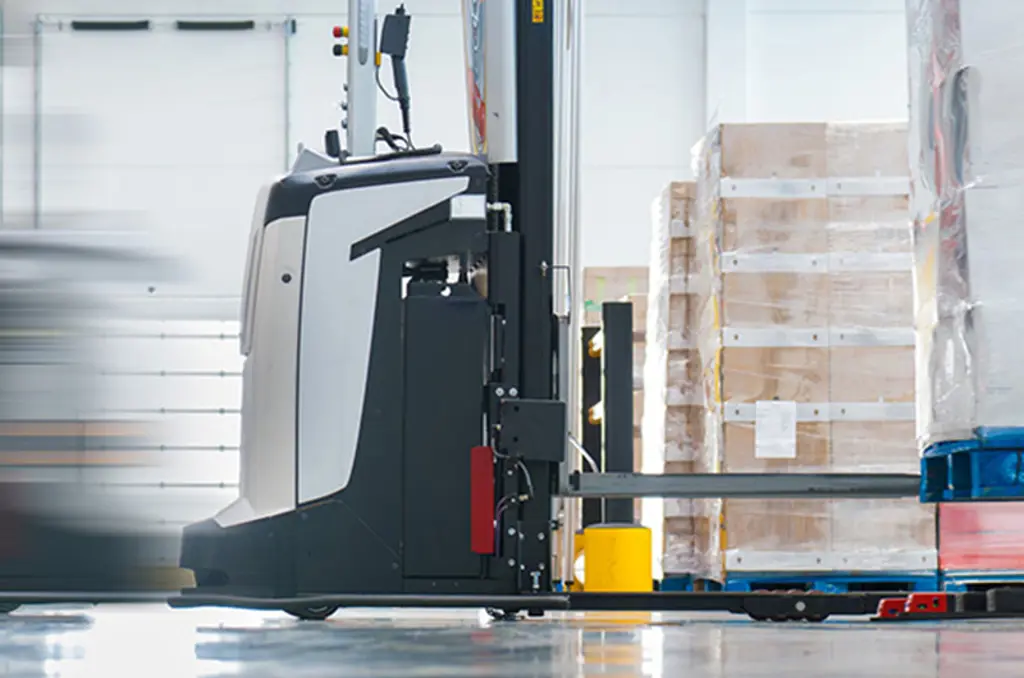 Een AVG vervoert een pallet in een magazijn voor geautomatiseerde materiaalbehandeling.