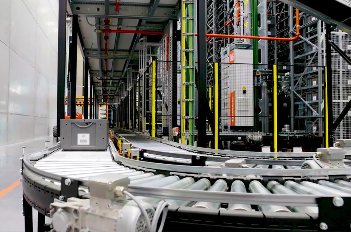 Geautomatiseerd transportbandsysteem voor magazijnen met rollenbanen en veiligheidshekken voor materiaalbehandeling.