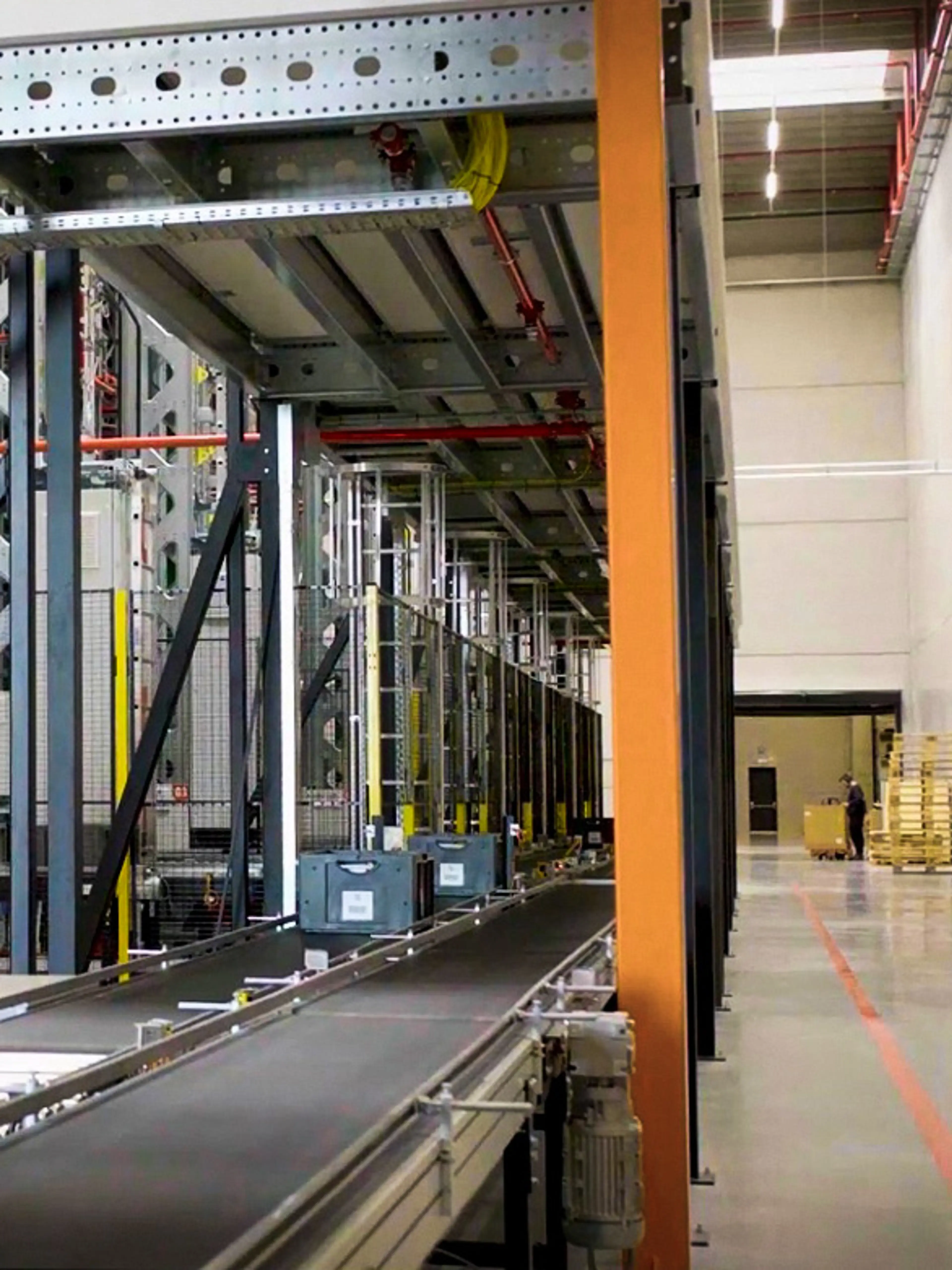 Werknemer die een transportband bij een magazijn oversteekt met veiligheidsbarrières op hun plaats