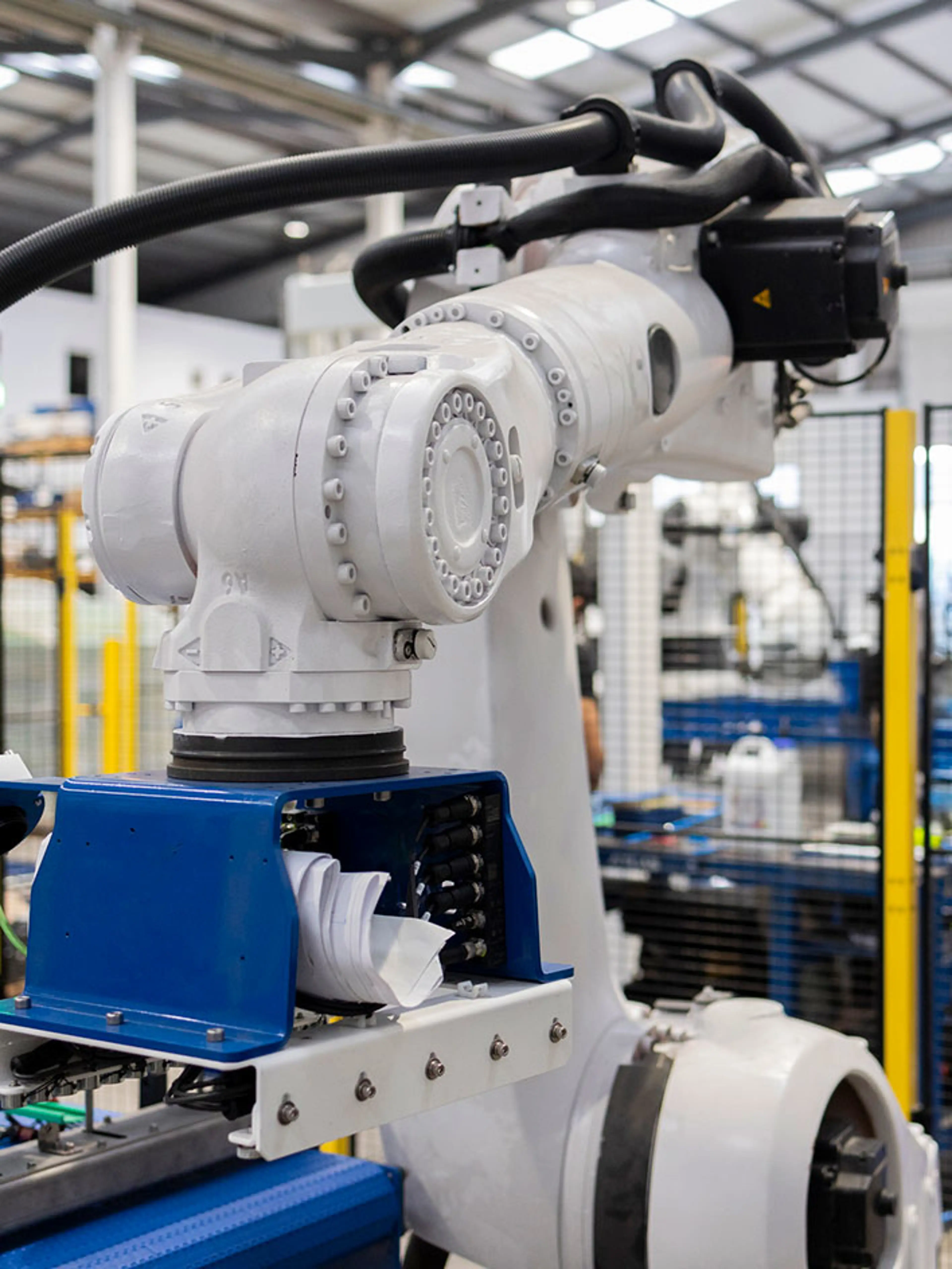Collaboratieve robot die pakketten in een magazijn met veiligheidsbarrières plaatst.