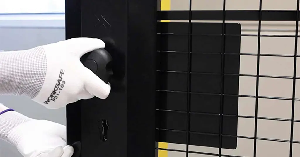 Hand met een cilinderpaniekslot gemonteerd op een zwart gaaspaneel 