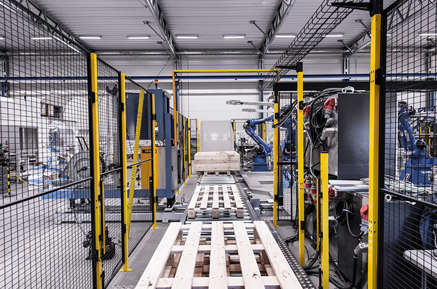 Robotarmen palletiseren kartonnen dozen in een beveiligde automatiseringscel